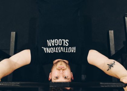 Bearded sportsman in t shirt with inscription exercising with weight while looking at camera
